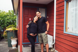 Young couple with pregnant woman in front of house they recently bought in Auckland, New Zealand.